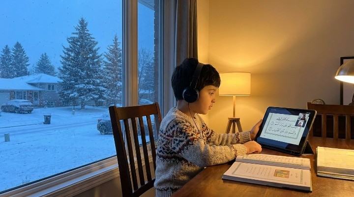 Child attending an online Quran class from home during a Canadian winter evening